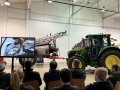 Personen in Halle mit Traktor und großem Bildschirm