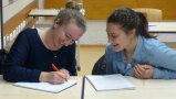 Zwei Schülerinnen besprechen sich an einem Tisch