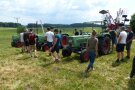 Personen stehen auf einem Feld vor zwei Traktoren.